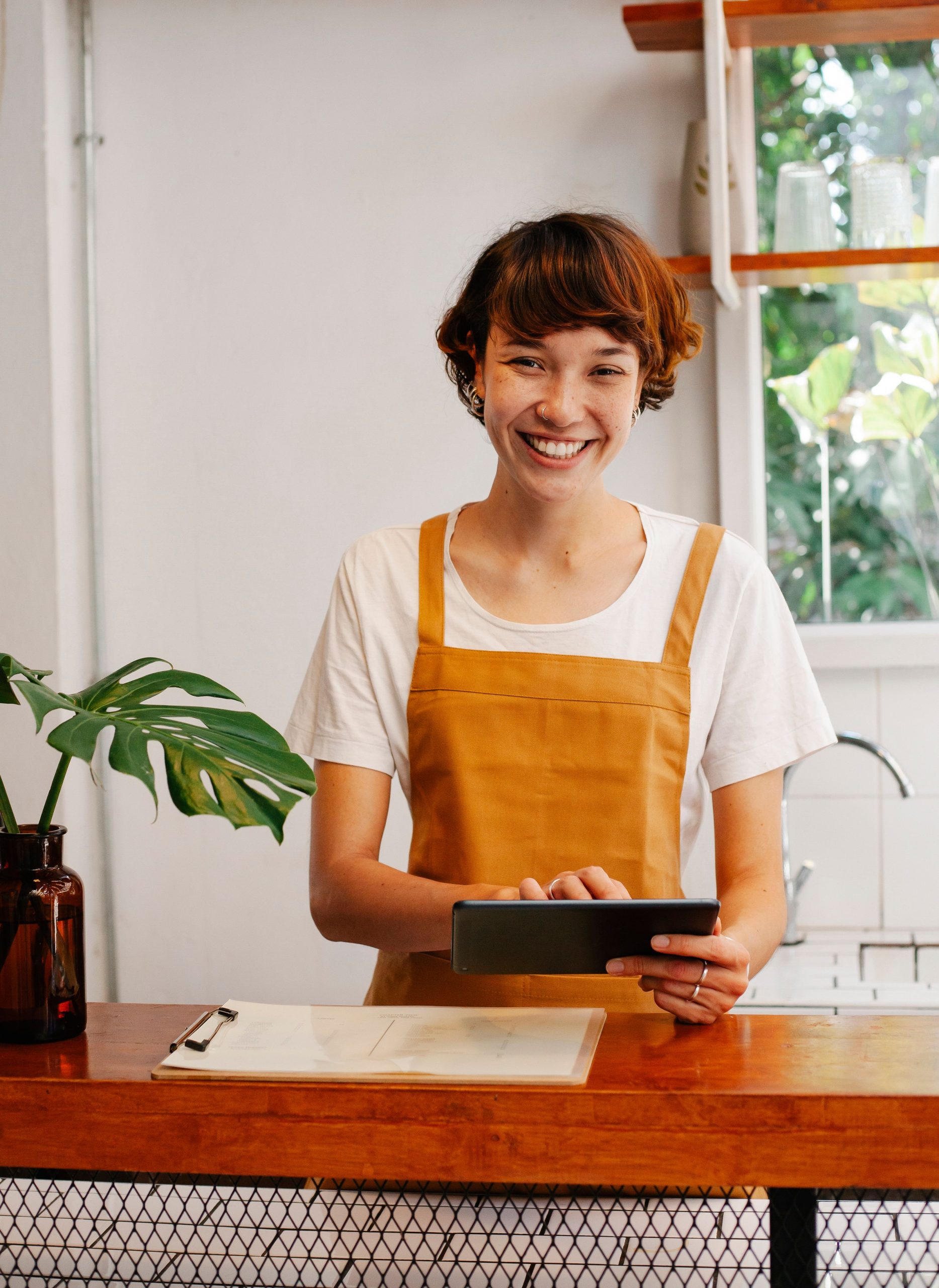 Commerçante souriante derrière son comptoir avec sa tablette POS